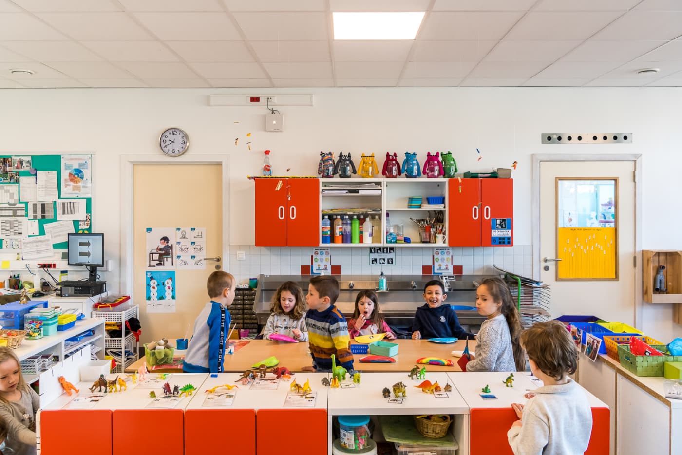 Leerlingen spelen en leren samen in een kleurrijk klaslokaal van een basisschool.